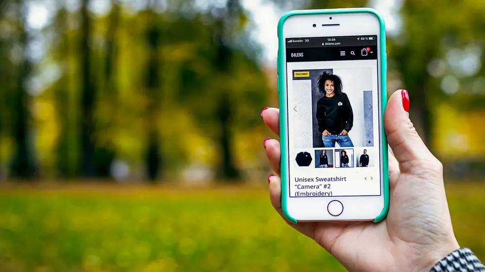 Erste Nachricht beim Online-Dating unterwegs: eine Hand hält ein Smartphone vor einem Park im Herbst