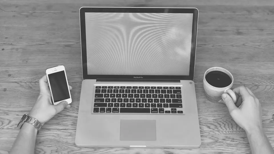 Sicher auf Dating Seiten: Smartphone, Laptop und eine Tasse Kaffee auf einem Tisch
