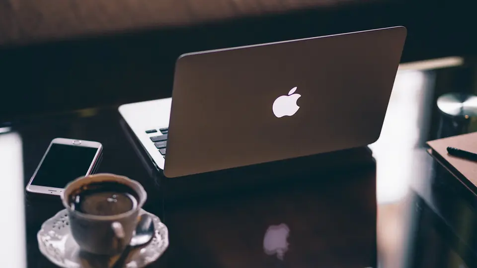 Love Scam erkennen am Rechner: Laptop und Smartphone auf einem dunklen Schreibtisch