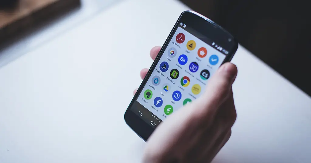 Dating Apps: eine Hand hält ein Smartphone mit vielen App-Symbolen