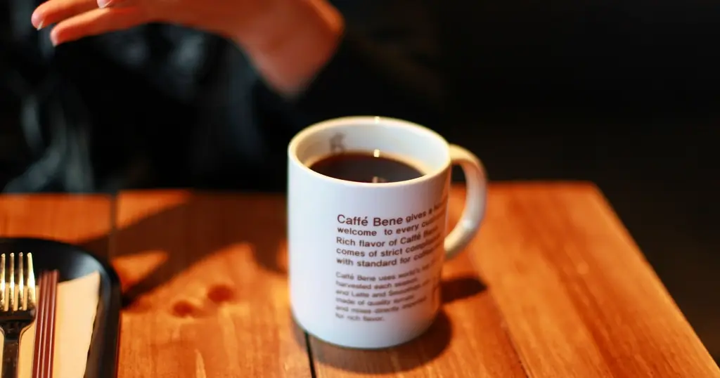 Erstes Date: eine Kaffeetasse auf einem Holztisch, daneben eine Hand